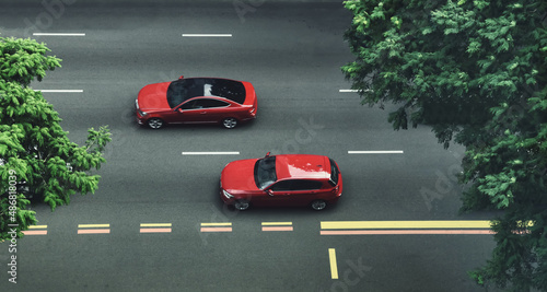 top view Two red cars cruising on a city street with trees.