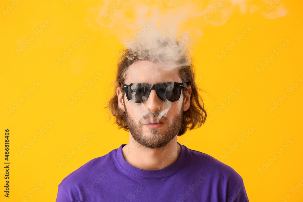 Fototapeta premium Smoking young man on yellow background