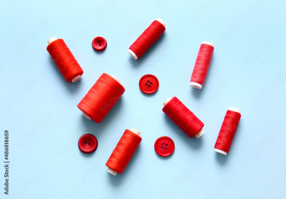 Thread spools and buttons on blue background Thread spools and buttons on blue background