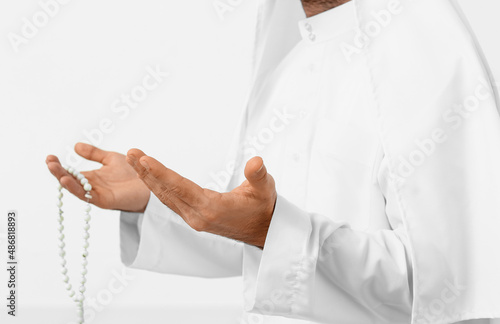 Praying young Muslim man on white background