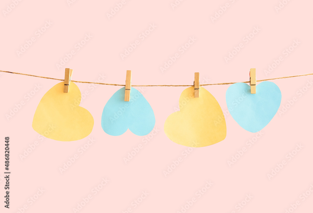 Blank cards in shape of hearts hanging on rope against color background. International Women's Day celebration Blank cards in shape of hearts hanging on rope against color background. International Women's Day celebration
