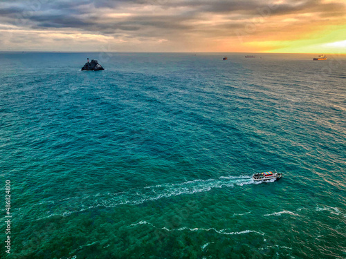 A boat passing by waving on the emerald sea at sunset