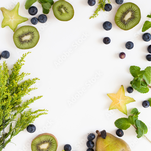 A top view of kiwis, blueberries, and star fruit on a white surface with space for text