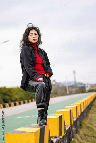 An Asian woman in a black leather coat outdoors
