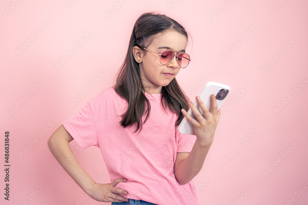 Stylish little girl with a smartphone on a pink background. Stylish little girl with a smartphone on a pink background.