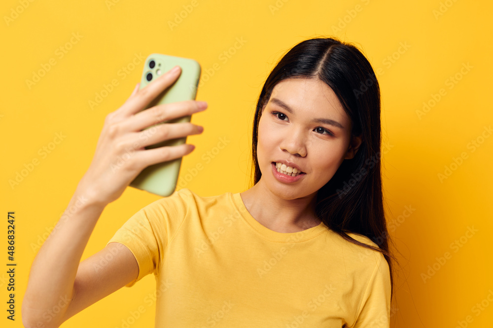 Portrait Asian beautiful young woman with a phone in her hands makes a selfie isolated background unaltered Portrait Asian beautiful young woman with a phone in her hands makes a selfie isolated background unaltered