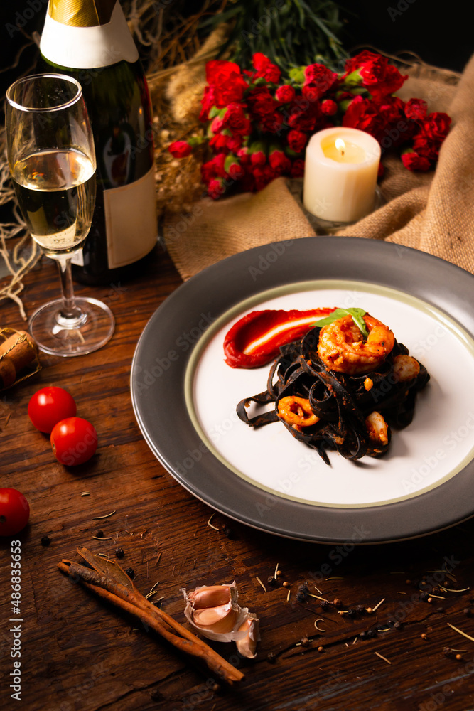 Squid-ink fettuccine with tomato sauce and shrimp in white dish serve with white wine.