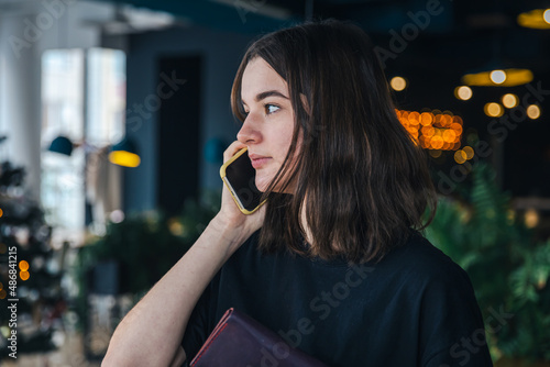 A young woman is talking on the phone with a wallet in her hands.