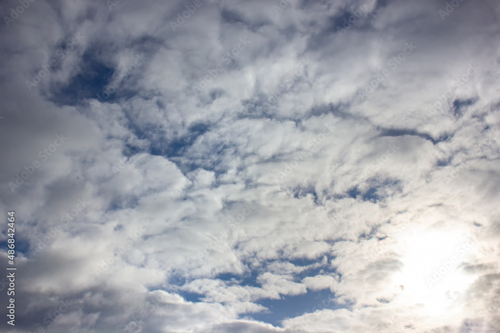 Obraz premium Bright sun behind white clouds. Sky background.