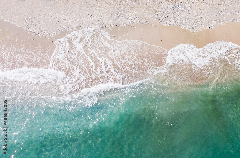 Top-down aerial view of a clean white sandy beach on the shores of a beautiful turquoise sea