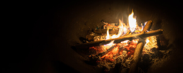 Bonfire, log fire, or campfire in dark background with flame, burned log wood, firewood in home fireplace for heating or camping
