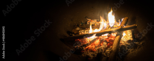 Bonfire, log fire, or campfire in dark background with flame, burned log wood, firewood in home fireplace for heating or camping photo