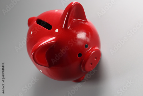 Red piggybank container on grey surface with hole for coins, empty ceramic pig for money