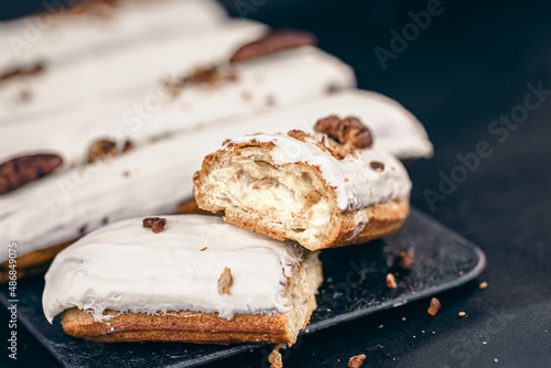 Close-up of eclairs in white glaze with pecans.