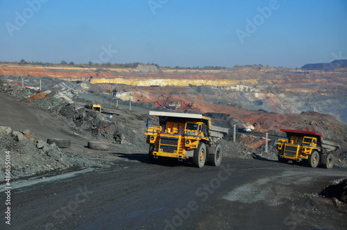 Obraz na płótnie Mining dump truck transports rock, iron ore along the side of the quarry