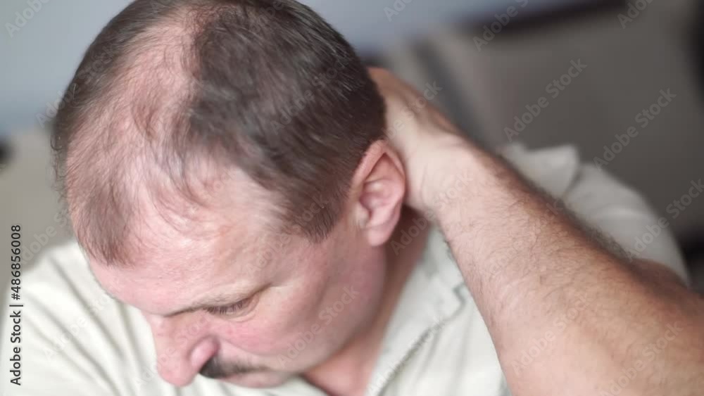An elderly mustachioed man with bald head rubs and massages neck joints with symptoms of pain in cervical spondylosis, osteoarthritis, stenosis, muscle spasms. Concept of healthcare, medicine products An elderly mustachioed man with bald head rubs and massages neck joints with symptoms of pain in cervical spondylosis, osteoarthritis, stenosis, muscle spasms. Concept of healthcare, medicine products