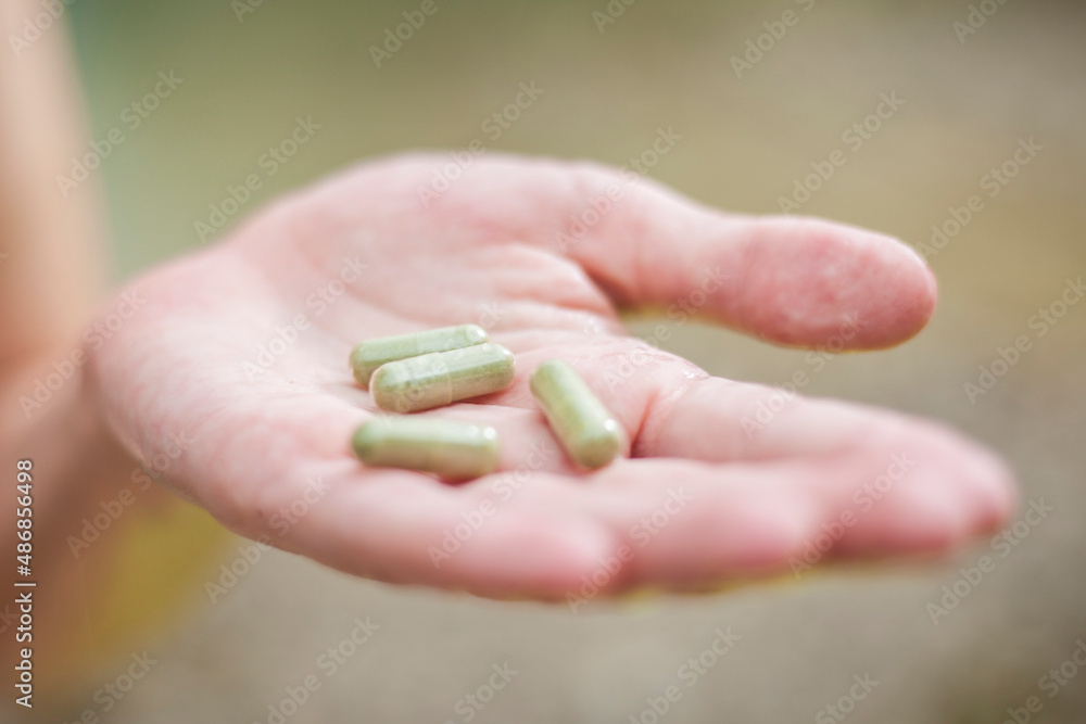 Female hand holding beige medicine pills Female hand holding beige medicine pills