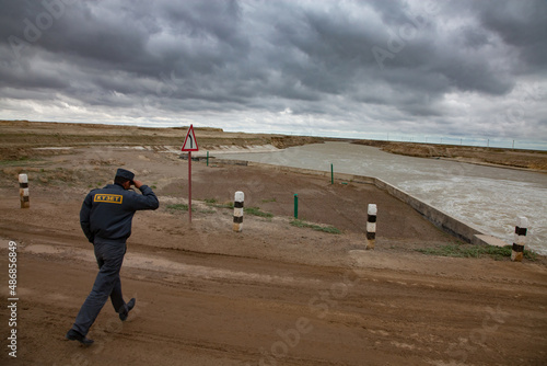 Kzylorda region, Kazakhstan - May 03, 2012: Aklak waterworks facility. Title: Security guard. Guardian run under strong wind. Turbulent water of Shardara river and stormy clouds. photo