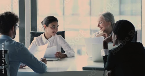 Young indian female specialist bring up proposal give plan idea review sales report on briefing with diverse teammates. Corporate workers listen to colleague expert speaking on conference at boardroom