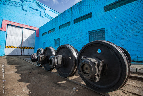 Blue vintage locomotive repair depot building. Train wheels on foreground. photo