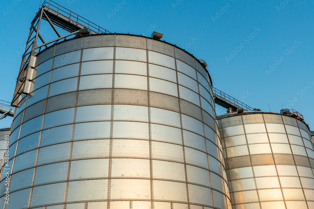 A large modern plant for the storage and processing of grain crops. view of the granary on a sunny day against the blue sky. End of harvest season. A large modern plant for the storage and processing of grain crops. view of the granary on a sunny day against the blue sky. End of harvest season.