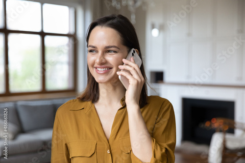 Fotótapéta Head shot happy beautiful young woman holding phone call conversation, communicating remotely with friends or family, discussing life news or sharing good ideas, standing alone in modern living room