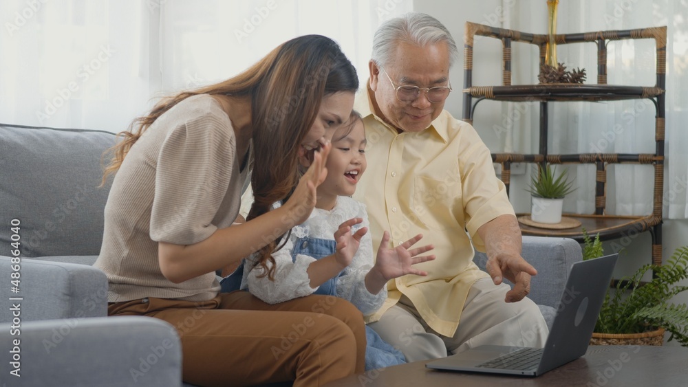 Happy family senior grandfather, daughter and granddaughter talking online via video chat using laptop computer with father, old grandpa embracing little grand child and mother in living room at home Happy family senior grandfather, daughter and granddaughter talking online via video chat using laptop computer with father, old grandpa embracing little grand child and mother in living room at home