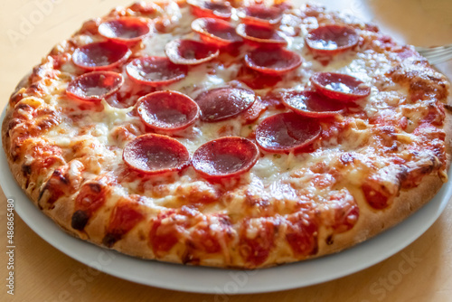 Delicious salami pizza in close-up macro view with cheese and tomato sauce as delicious italian delicacy and diet fast food lunch for hungry teenagers eating unhealthy nutrition snacks in pieces