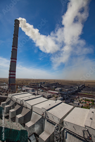 GRES-1 thermal power station roof. Grey raw coal bunkers. Smoke stack with white smoke left. Dry grass steppe and blue sky. Ekibastuz, Pavlodar region, Kazakhstan. photo