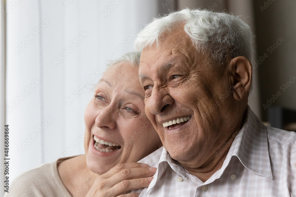 Happy cheerful senior couple looking away candid close up portrait. Elderly husband and wife talking, chatting, laughing, joking, hugging with love, gratitude, tenderness, having fun Happy cheerful senior couple looking away candid close up portrait. Elderly husband and wife talking, chatting, laughing, joking, hugging with love, gratitude, tenderness, having fun