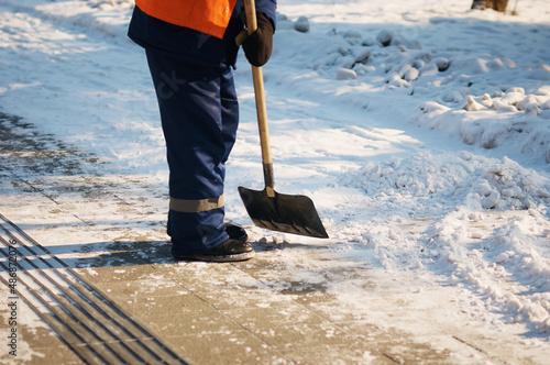 Wallpaper Mural A city utility worker in a bright orange vest clears snow from city streets. Clearing the footpath from snow using a shovel. Sunny winter day. Tactile tiles for blind people. Torontodigital.ca