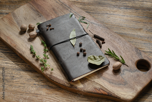 Notebook for recipes with spices on a wooden cutting board. Selective focus