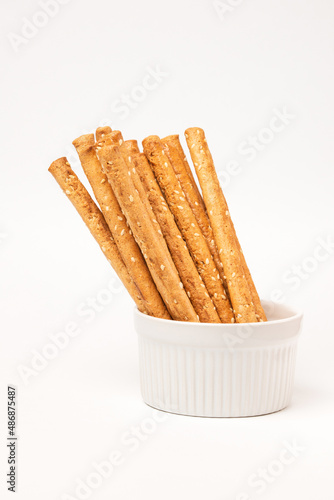 Classic crispy bread sticks grissini with sesame seeds in white form. Traditional Italian pastry breadsticks on white background with copy space