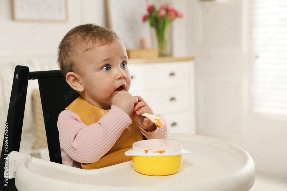Cute little baby wearing bib while eating at home Cute little baby wearing bib while eating at home