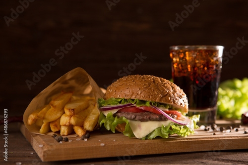 American snack with big burger and glass cola on wooden table