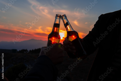 cheering toast beverage alcoholic drink bottles in beautiful evening dark and moody sunset silhouette scene