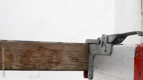 Driver secures a truck load cargo using an aluminium bar. Secure cargo fasten