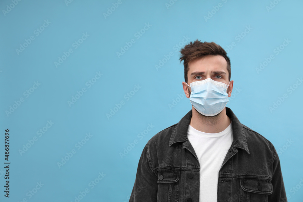 Portrait of man with medical mask on light blue background, space for text Portrait of man with medical mask on light blue background, space for text