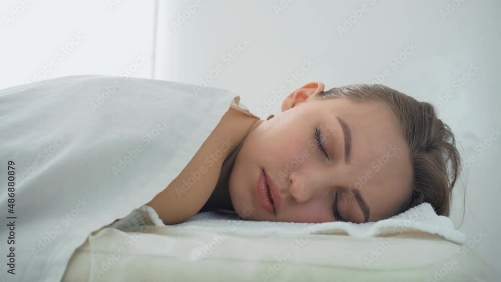 Young woman lying with eyes closed at cosmetologist appointment. Concept of body care and alternative medicine Young woman lying with eyes closed at cosmetologist appointment. Concept of body care and alternative medicine