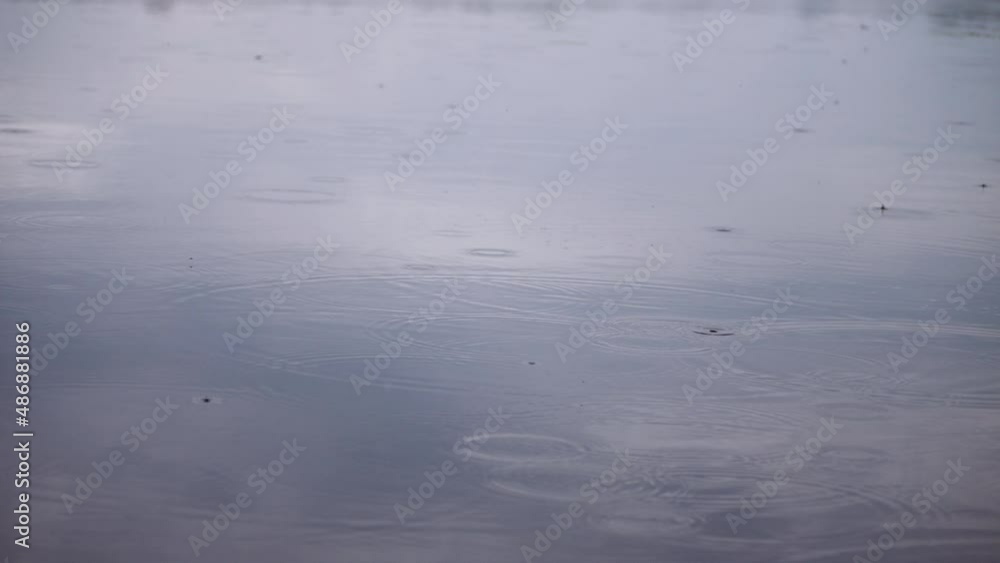 Close-up rain of small drops in spring, while fishing, fall on the surface of the river, making many relaxing circles. Close-up rain of small drops in spring, while fishing, fall on the surface of the river, making many relaxing circles.