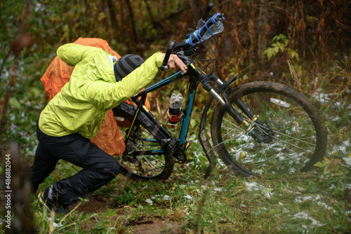 Tourist pushing bicycle in hill in frost autumn forest