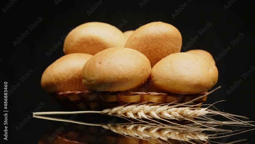 Bread buns on wooden plate on black background rotate on mirror table ...