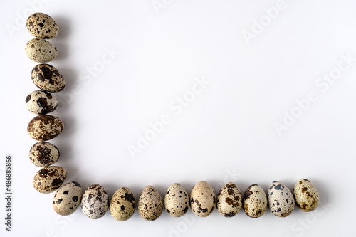 frame of quail eggs on the perimeter of two sides on a white background. Copy space.