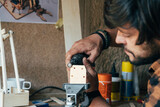 An Anonymous Carpenter Working in his Workshop. 
Close up photo of man hands using mini electric sander at his workbench.