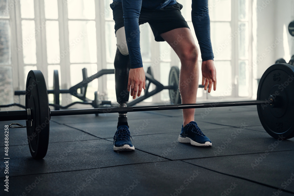 Fototapeta premium Close up shot of male Paralympic athlete with prosthetic leg about to lift a barbell