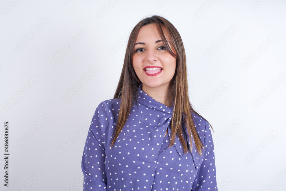Young arab woman wearing polka-dot clothes over white backgtound with happy and funny face smiling and showing tongue. Young arab woman wearing polka-dot clothes over white backgtound with happy and funny face smiling and showing tongue.