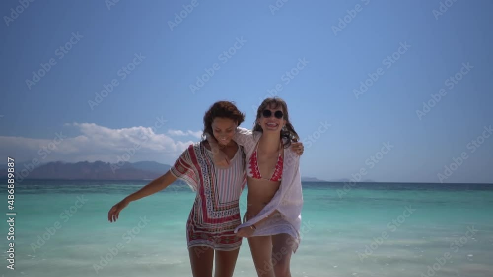 A couple of bikini girls in love have fun on the beach, hugging, laughing and they are happy being together A couple of bikini girls in love have fun on the beach, hugging, laughing and they are happy being together