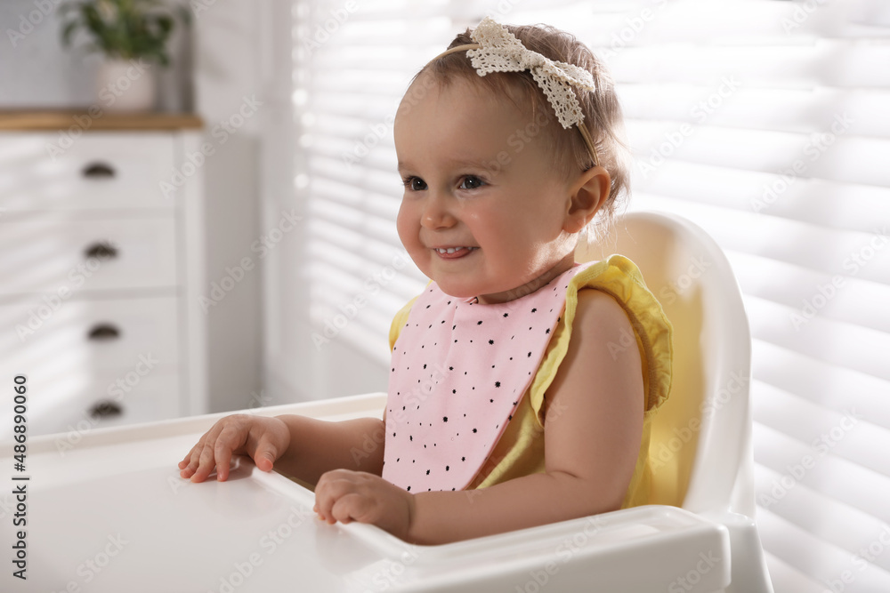 Cute little baby wearing bib in highchair at home Cute little baby wearing bib in highchair at home