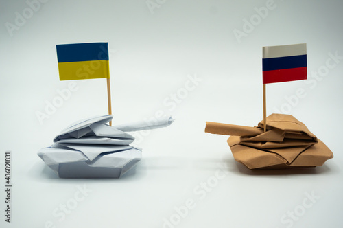 Paper folded tank with Ukrainian and Russian flags. Placed against each other.Ukraine crisis and Conflict.border tensions.Local war.Relationship.International situation theme.warface. photo