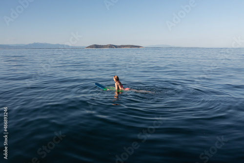 A beautiful young woman relaxes on a SUP board in the sea. Summer holiday idyllic
